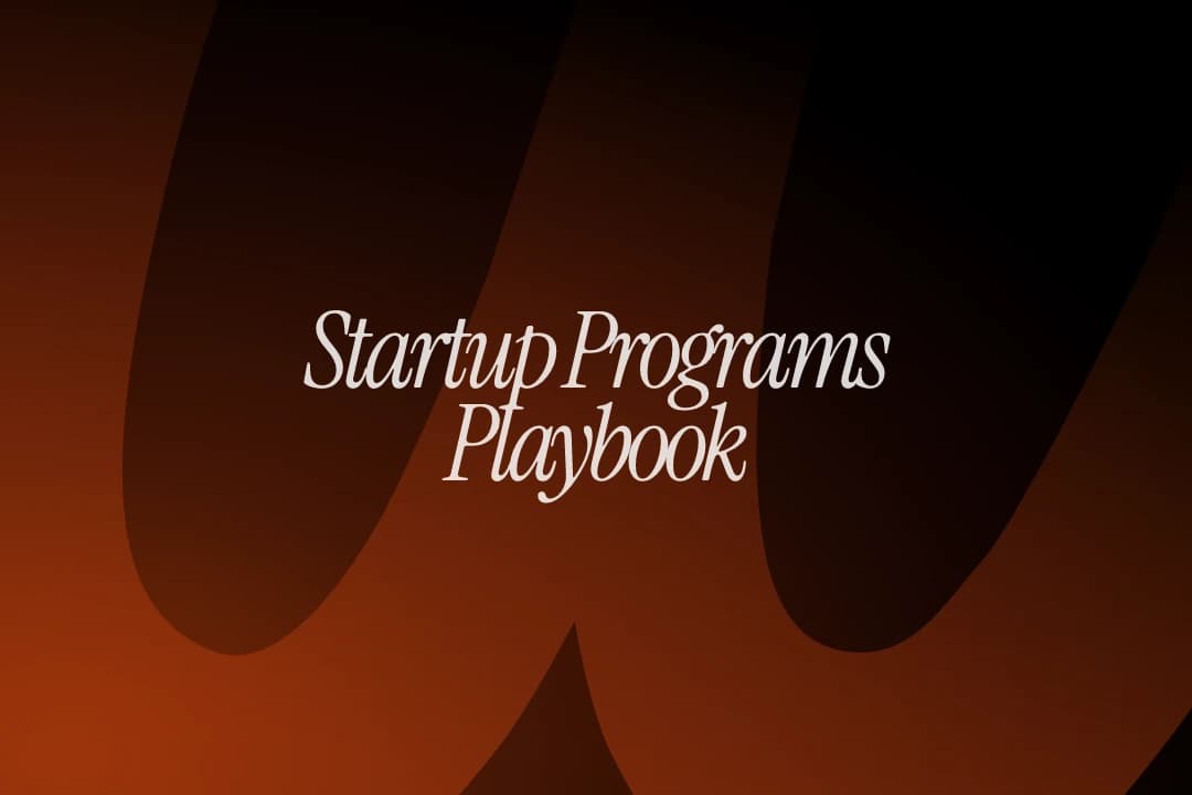 Hand holding a glowing chain of AI app icons beside the title Startup Programs Playbooks